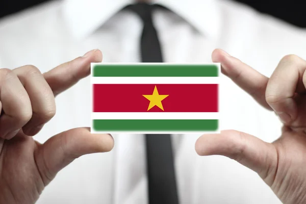 Podnikatel drží vizitku s Surinamská vlajka — Stock fotografie