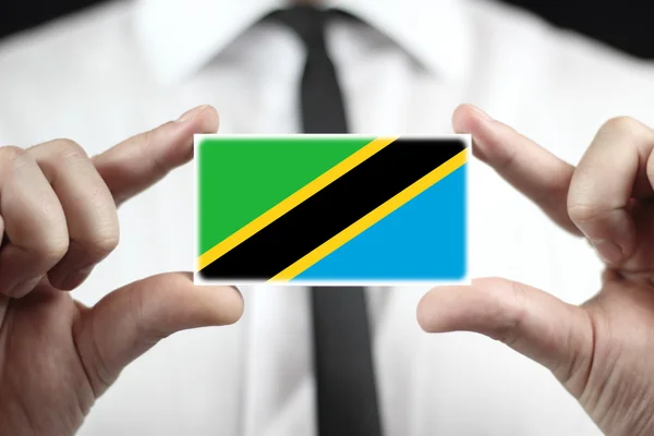 Podnikatel drží vizitku s vlajka Tanzanie — Stock fotografie