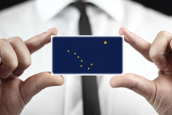 Businessman holding a business card with Alaska State Flag — Stock Photo, Image