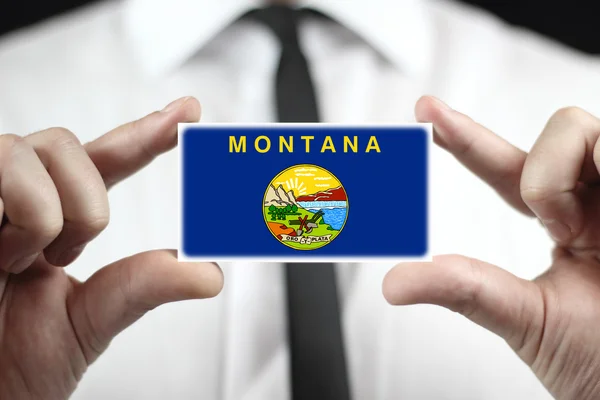 Бизнесмен, держащий визитку с флагом штата Монтана — стоковое фото