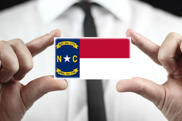 Бизнесмен с визитной карточкой под флагом штата Северная Каролина — стоковое фото