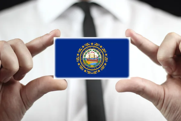 Zakenman houden een visitekaartje met vlag van new hampshire — Stockfoto