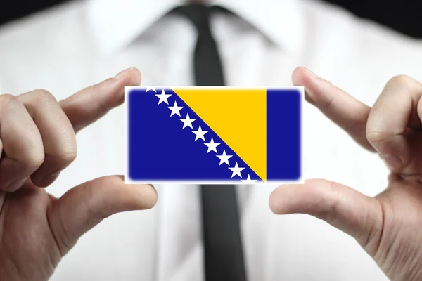 Biznesmen posiadający wizytówkę z Flagą Bośni i Hercegowiny — Zdjęcie stockowe