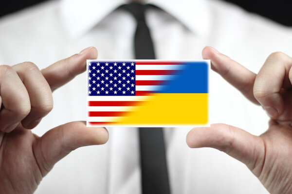 Бизнесмен с флагом Украины и США имеет визитную карточку
