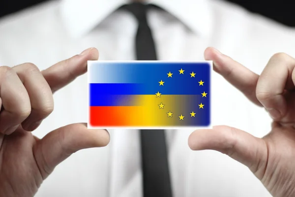 Empresario con tarjeta de visita con bandera de Ucrania, la UE y Rusia —  Fotos de Stock