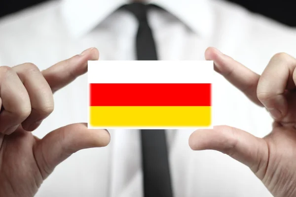 Geschäftsmann mit Visitenkarte mit südossetischer Flagge — Stockfoto