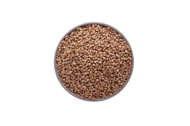 Beyaz arka planda kabın içinde çiğ karabuğday var. Üst görünüm