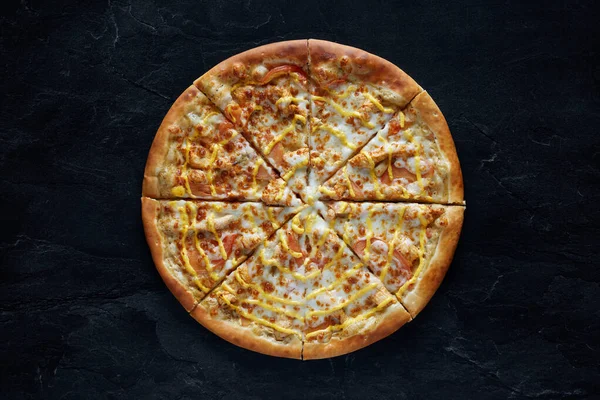 Pizza met kip, kaas en tomaten op een zwarte stenen achtergrond. Bovenaanzicht — Stockfoto