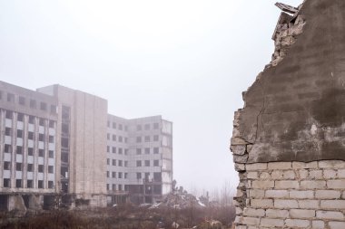 Bir binanın harabelerine yakın plan bir tuğla duvar ve sisin içinde gri bir gökyüzü. Arkaplan