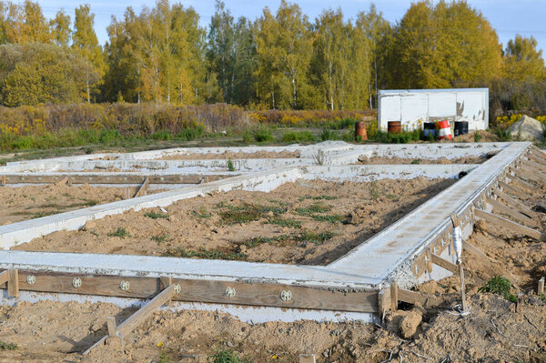The foundation of a poured concrete solution of a country house in close-up at the beginning of construction against the background of a forest. Background.