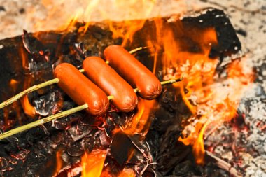 Biftek sosisleri ateşte kızartılır. Geçmişi. Konsept bir kamp mutfağı..