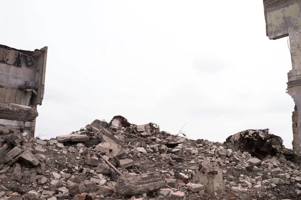 建物の遺跡と雲と灰色の空の背景に建設土石流のコンクリートの残骸の山 — ストック写真
