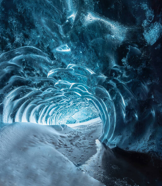 Blue crystal ice cave entrance and an underground river beneath the glacier located in the Highlands in Iceland. Photo taken in Iceland.