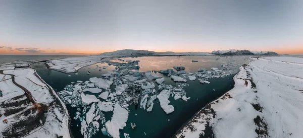 Flygdrönare panorama över berömda sjön Joekulsarlon glacial lagun och diamant stranden med sina isberg och isflak på Island under solnedgången skymning på vintern. — Stockfoto