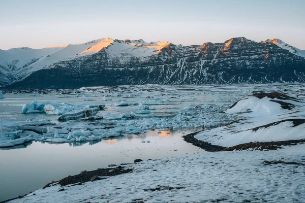 Letecké dron panorama slavného jezera Joekulsarlon ledovcové laguny a diamantové pláže s ledovci a ledových ker na Islandu během západu slunce soumraku v zimě. — Stock fotografie