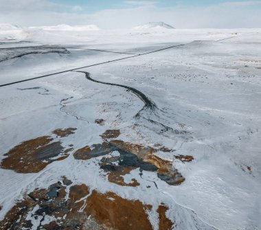 Yerden gelen sıcak buharlı hava aracı panoraması. Hver, Myvatn 'da jeotermal alan. Kar ve turuncu zemin ile kaplı arazi.