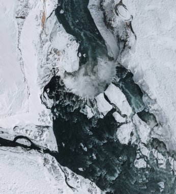 Godafoss Şelalesi 'nin insansız hava aracı görüntüsü, İzlanda, yüksek bir açıdan çekilmiş. Güçlü çağlayanın, nehrin ve karın havadan görünüşü kayaları kaplıyordu. Sonbahar sonu, kış başlangıcı sahnesi.