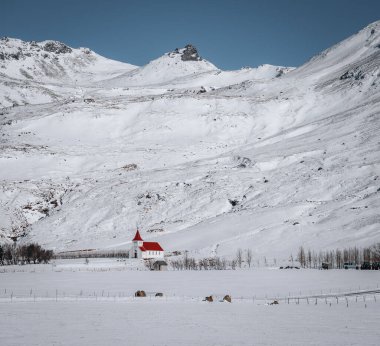 Traditional red church set against the snowy mountains above Vik I Myrdal on the South coast of Iceland