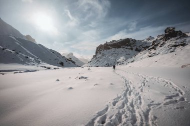 Two friends hiking in and winter iceland nature in highlands through snow covered mountains on a beautiful day with blue sky and sun.