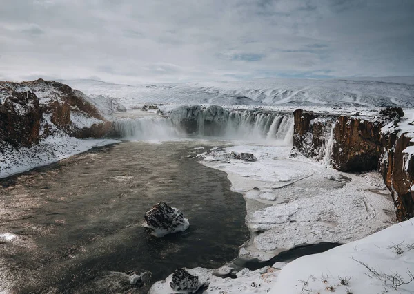 Ujęcie z drona wodospadu Godafoss, Islandia, zrobione z wysokiego kąta. Widok z lotu ptaka na potężne skały kaskadowe, rzeczne i pokryte śniegiem. Późna jesień, wczesna zima. — Zdjęcie stockowe