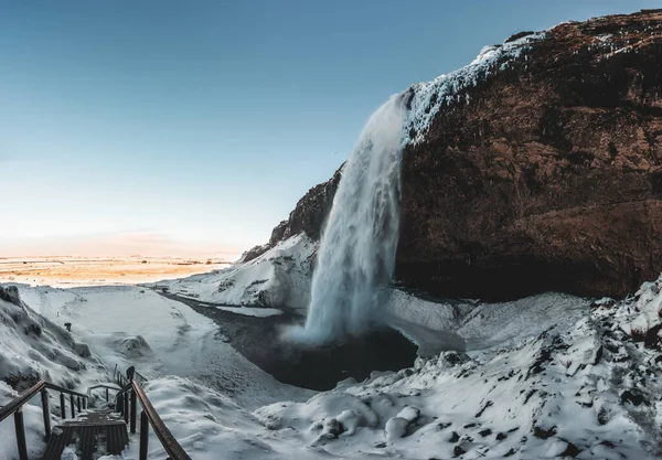 Cascade Seljalandsfoss en Islande en hiver avec ciel bleu et neige et paysage gelé. — Photo