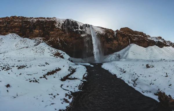 Seljalandsfoss waterfall in Iceland during winter with blue sky and snow and frozen landscape. — Stock Fotó