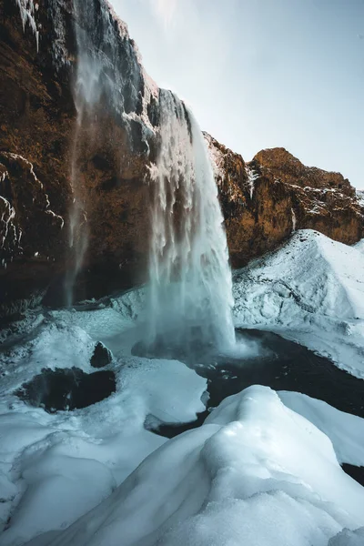 Seljalandsfoss waterfall in Iceland during winter with blue sky and snow and frozen landscape. — Stockfoto