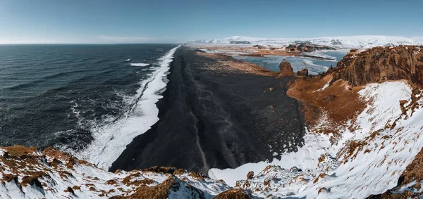 Kilátás Dyrholaey világítótorony Izlandon néz ki a fekete homokos strand alatt télen a hó és a gyönyörű napos időjárás. — Stock Fotó