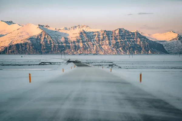 Zimní cesta v sněhovou vánici. Navátý sníh přes silnici. Obtížně jízdní podmínky v zimě na Islandu. Slunečné, ale větrné den, problémy typické islandské trasy. Islandský kurzy bezpečné jízdy. — Stock fotografie
