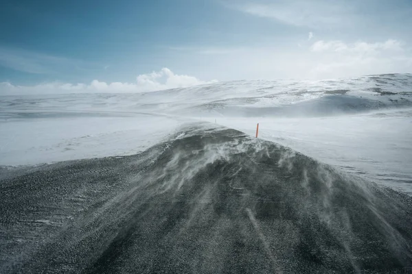 Télen a hó hófúvás út. Hófúvás, az út túloldalán. Nehéz vezetési körülmények között a téli szezonban, Izland. Napos, de szeles nap, tipikus Izlandi route bajok. Izlandi biztonság vezetés. — Stock Fotó