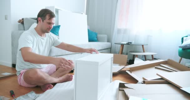 Vylepšení domova. muž sestavuje nábytek v bytě — Stock video