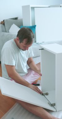 ev tadilatı. Bir adam bir dairede dikey olarak mobilya montajı yapar.