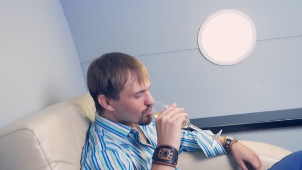 Bel homme dans la cabine d'un avion de classe affaires buvant du champagne dans un verre — Video