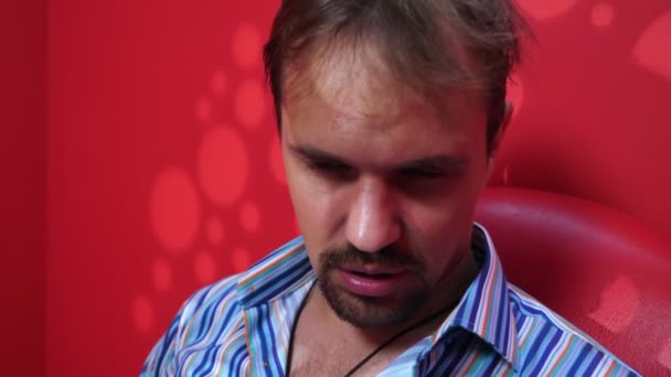 Retrato de un joven guapo en intoxicación alcohólica sobre fondo rojo con iluminación — Vídeos de Stock