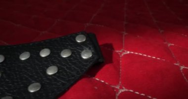 detailed, extreme close-up of a black leather eye mask on a red blanket