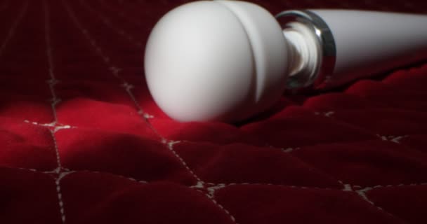 Detailed, extreme close-up of a white vibrator on a red blanket — Αρχείο Βίντεο