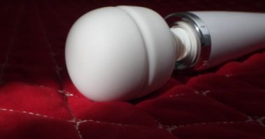 detailed, extreme close-up of a white vibrator on a red blanket