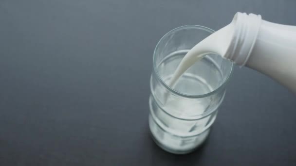 Top view of pouring yogurt into a glass from a white plastic bottle. brown background — Vídeos de Stock