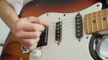 closeup of male hands with a plectrum playing the electric guitar