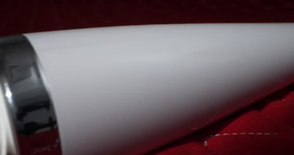 Detailed, extreme close-up of a white vibrator on a red blanket — Stock video