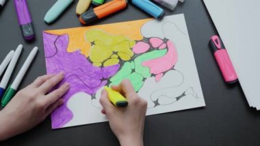 neurographics close-up top view. a female hand paints a drawing with black neurographic lines with colored markers