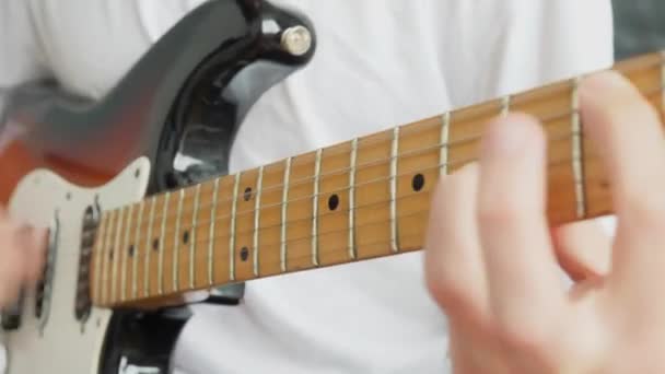 Close-up male hands clamp the strings on the fretboard of an electric guitar — Stockvideo