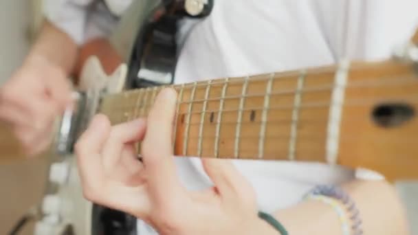 Close-up male hands clamp the strings on the fretboard of an electric guitar — ストック動画