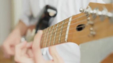 close-up male hands clamp the strings on the fretboard of an electric guitar