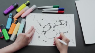 close-up of neurographics, top view. female hand draws a pattern with black neurographic lines on a white sheet