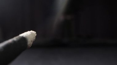 extremely close-up detailed Incense, incense sticks smoldering with clouds of smoke on a dark background