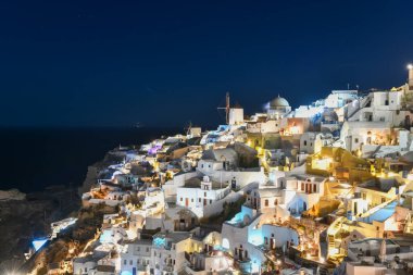 Klasik Oia ve Santorini geceleri Yunanistan 'daki binalarla gökyüzüne yükseliyor.