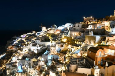 Klasik Oia ve Santorini geceleri Yunanistan 'daki binalarla gökyüzüne yükseliyor.