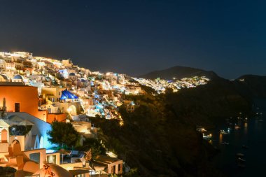 Klasik Oia ve Santorini geceleri Yunanistan 'daki binalarla gökyüzüne yükseliyor.