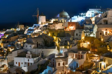 Klasik Oia ve Santorini geceleri Yunanistan 'daki binalarla gökyüzüne yükseliyor.
